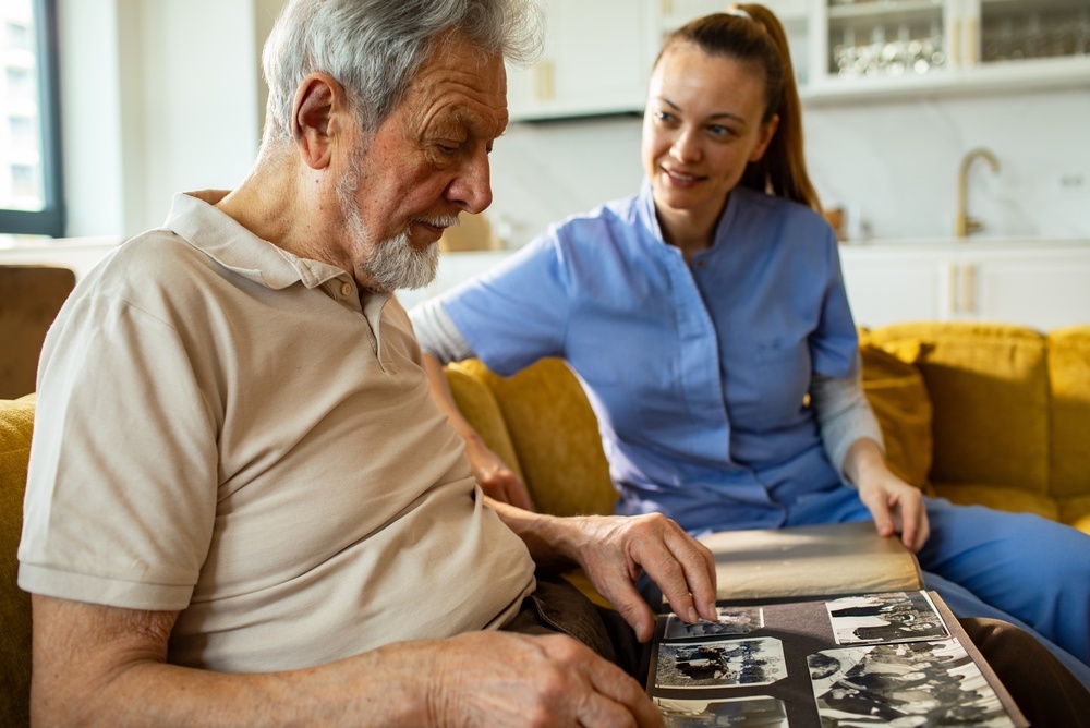 Caregiver and senior man reviewing photo album at home