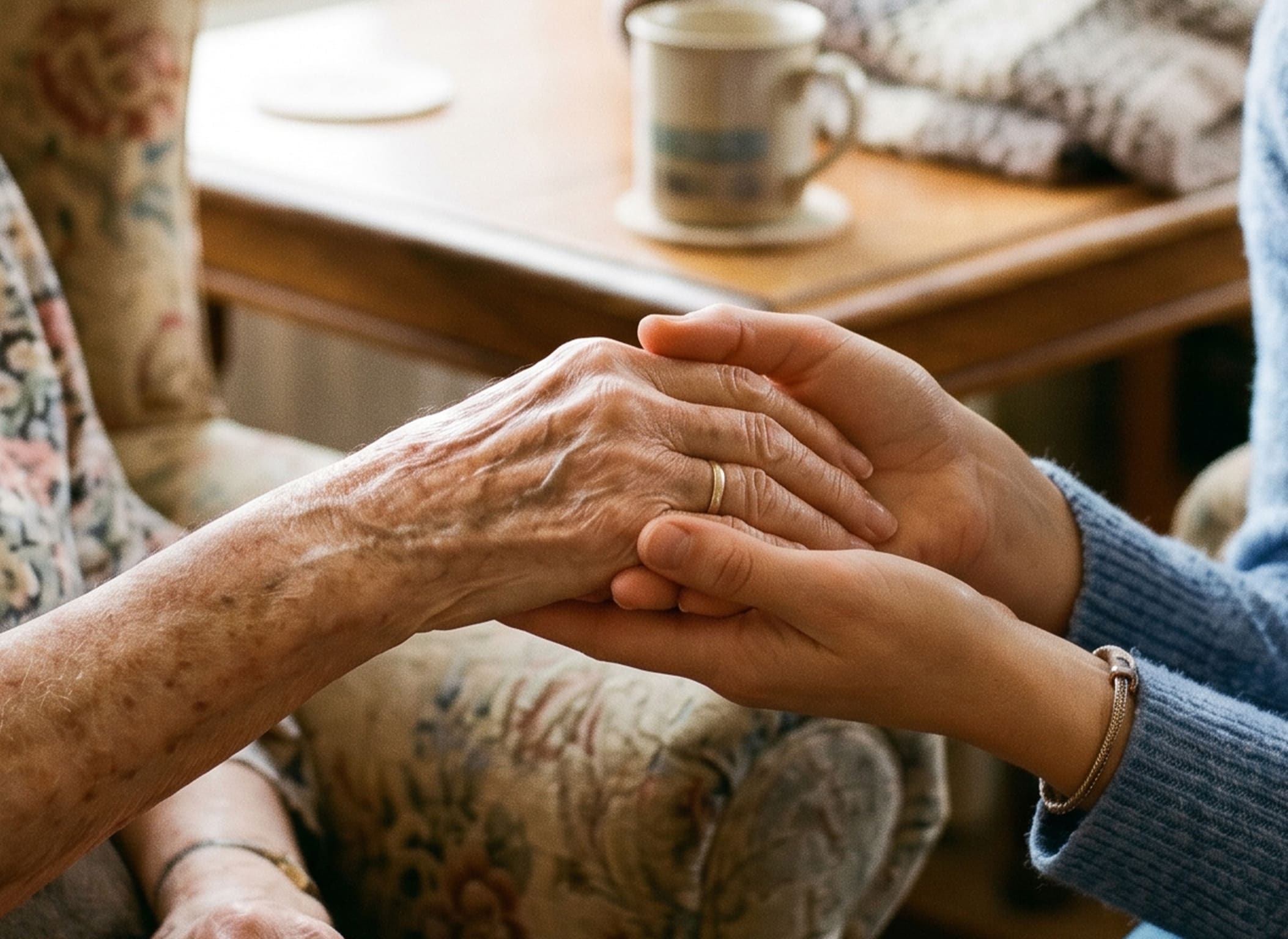 elderly hand being held between the two hands of another person