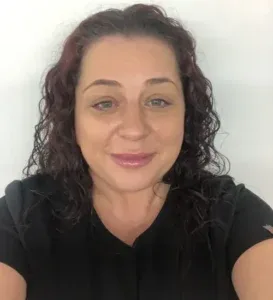 Women looking directly at the camera with curly dark hair and a black top on